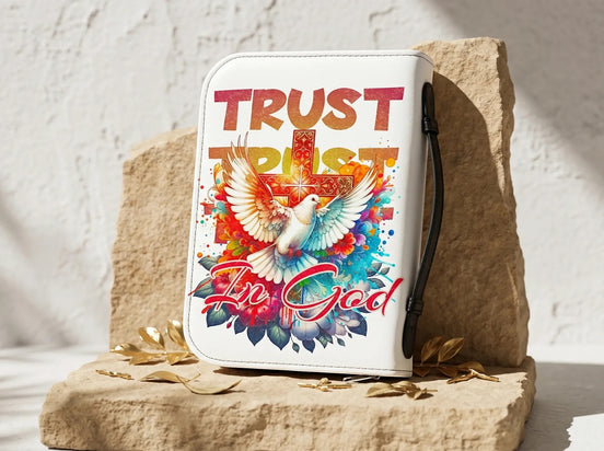 Couverture de Bible Essences Agape blanche avec inscription "Trust in God", colombe et croix colorées, poignée latérale.