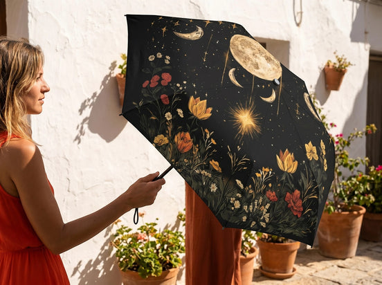 Parapluie pliant Essences Agape noir avec imprimé lune, étoiles et fleurs colorées. Design ésotérique et poétique.