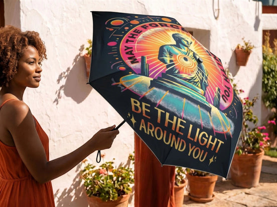 Parapluie pliant Essences Agape avec illustration spirituelle et message "Be the Light Around You". Toile noire avec motif coloré.