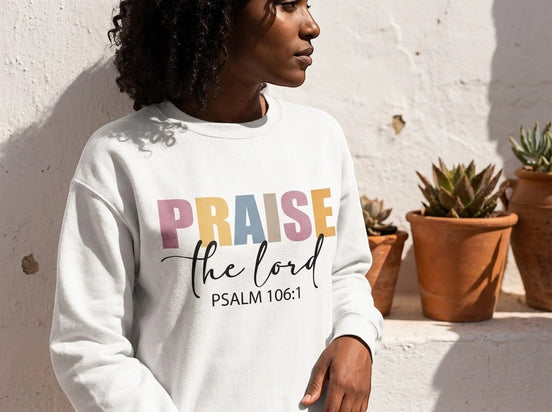 Sweatshirt blanc à col rond Essences Agape avec inscription "Praise the Lord - Psalm 106:1" et illustration d'ange au dos.