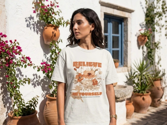 Essences Agape t-shirt blanc cassé avec inscription "Believe in Yourself" et bouquet floral, coupe unisexe.
