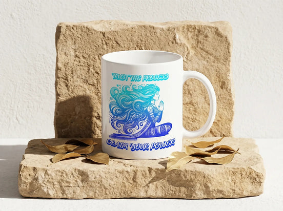 Tasse à café blanche Essences Agape avec motif méditation bleu et turquoise, texte "Trust the process" et "Claim your power".