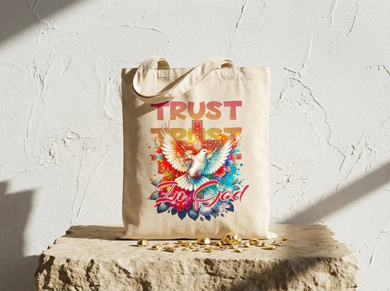 Tote bag en toile beige Essences Agape avec un motif d'ange, une colombe et une croix, texte "Trust In God". Idéal pour le shopping ou comme sac de courses.