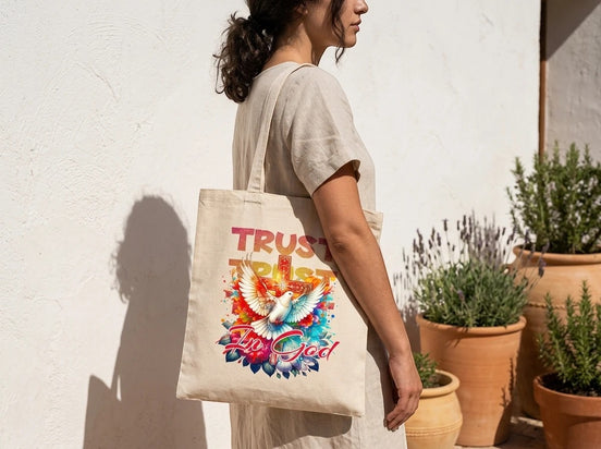 Essences Agape tote bag en toile beige avec un motif d'ange, une colombe et une croix, texte « Trust God ».
